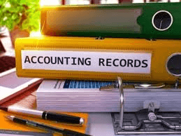 Picture of a stack of files and binders, one is labeled "Accounting Records".