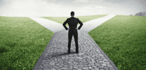 Man standing with his back to camera at a fork in a brick path.